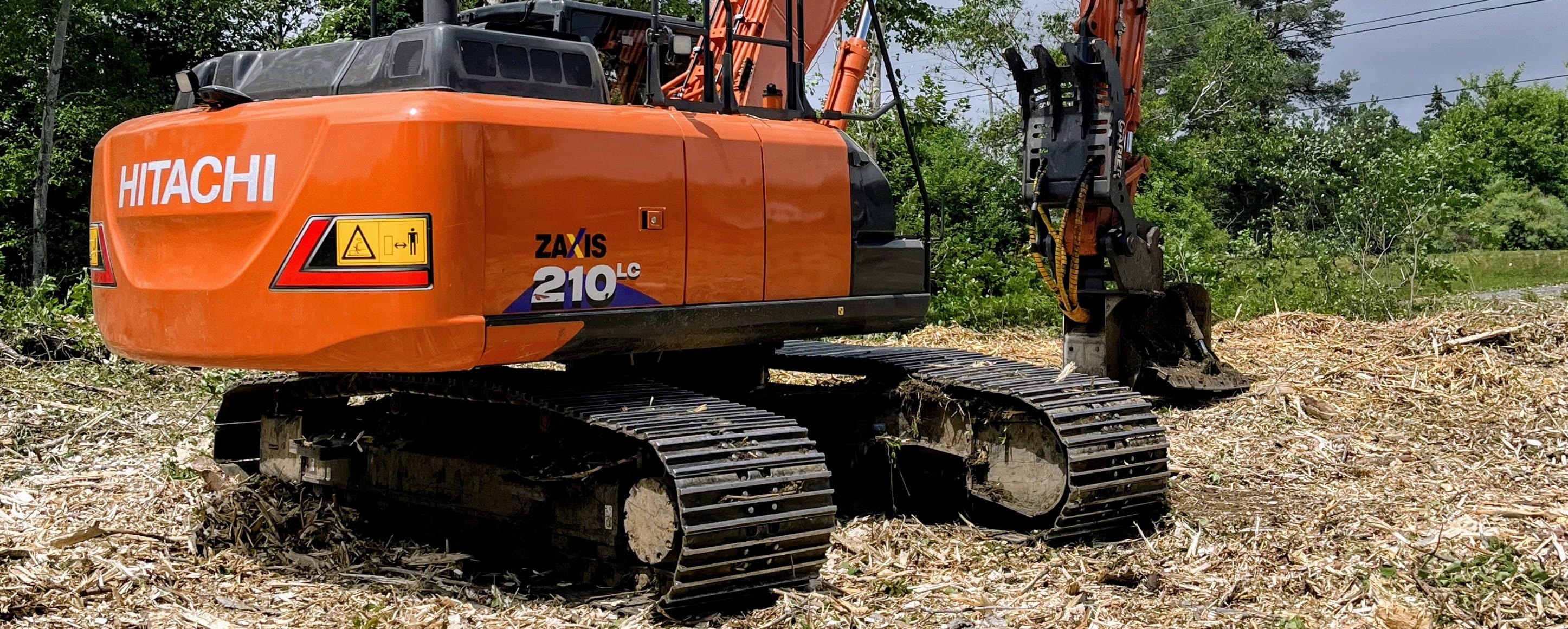 Excavator with mulching head clearing a residential lot